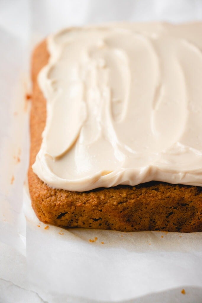 Frosted, baked carrot cake on top of parchment paper.