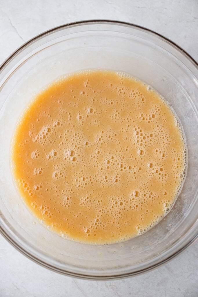 A large glass bowl with wet ingredient mixture.