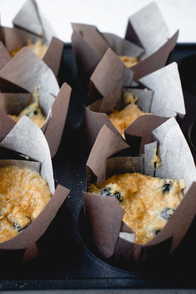A muffin tin with 6 batter-filled liners.